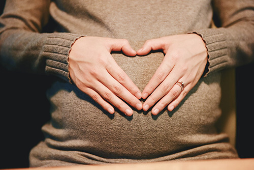 femme enceinte qui forme un coeur avec ses mains