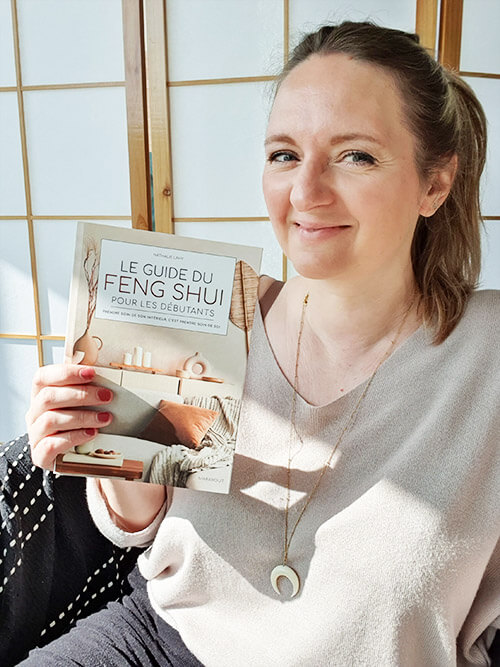 Nathalie Lahy, formatrice et consultante en Feng Shui traditionnel, tenant son livre “Le Guide du Feng Shui”.